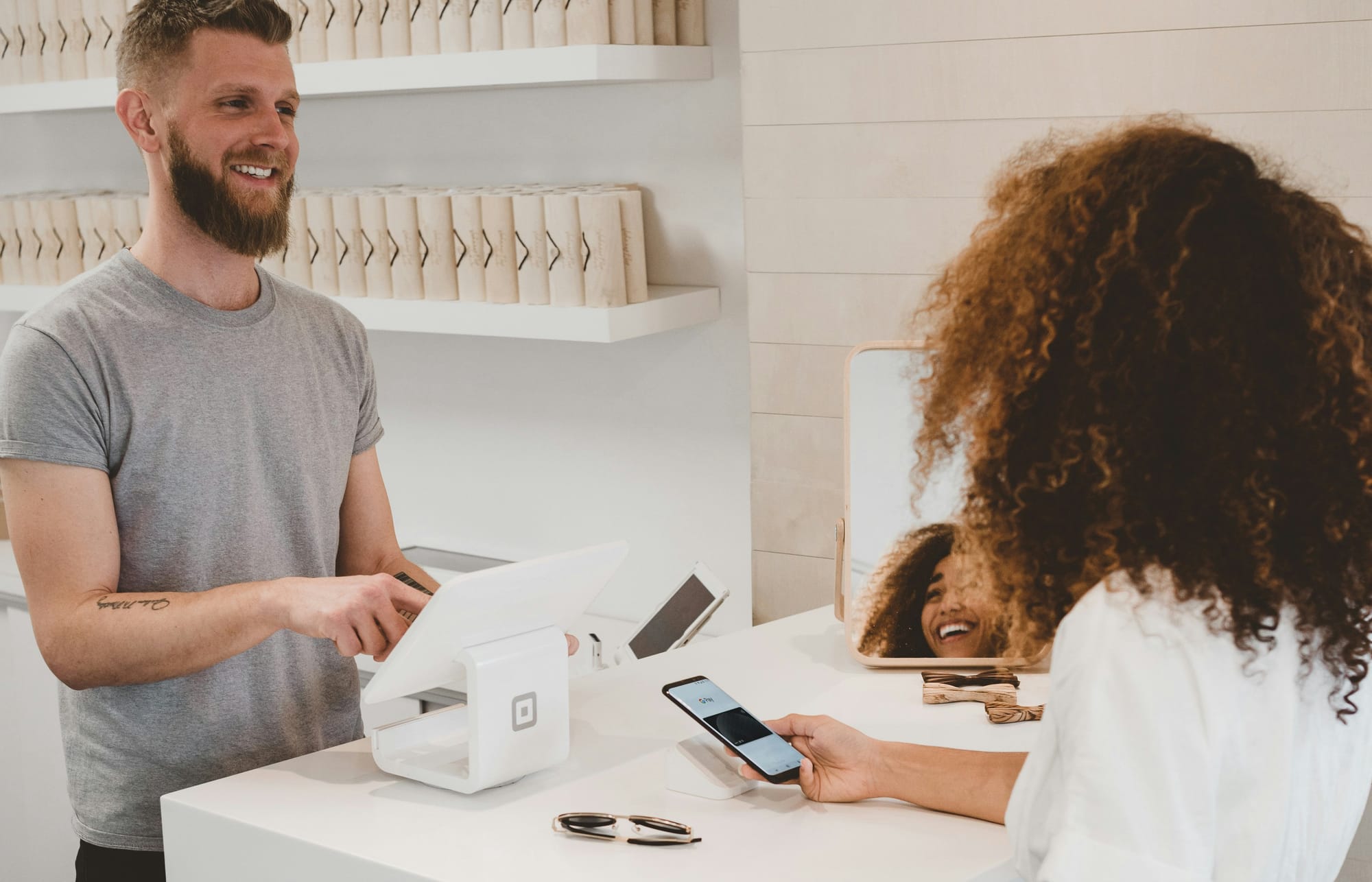 A small business owner helping a customer in person while the desk phone rings